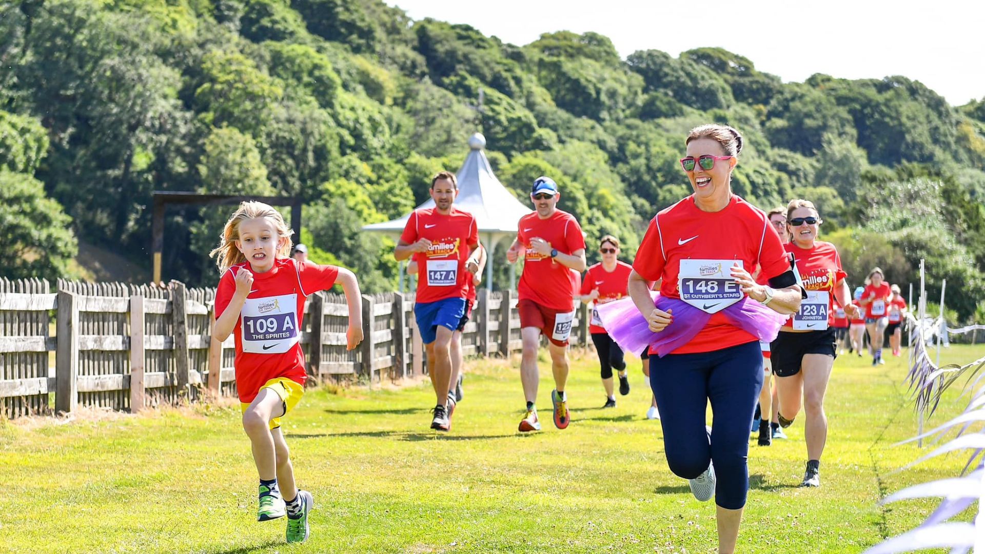 Families running together in red t-shirts in a field