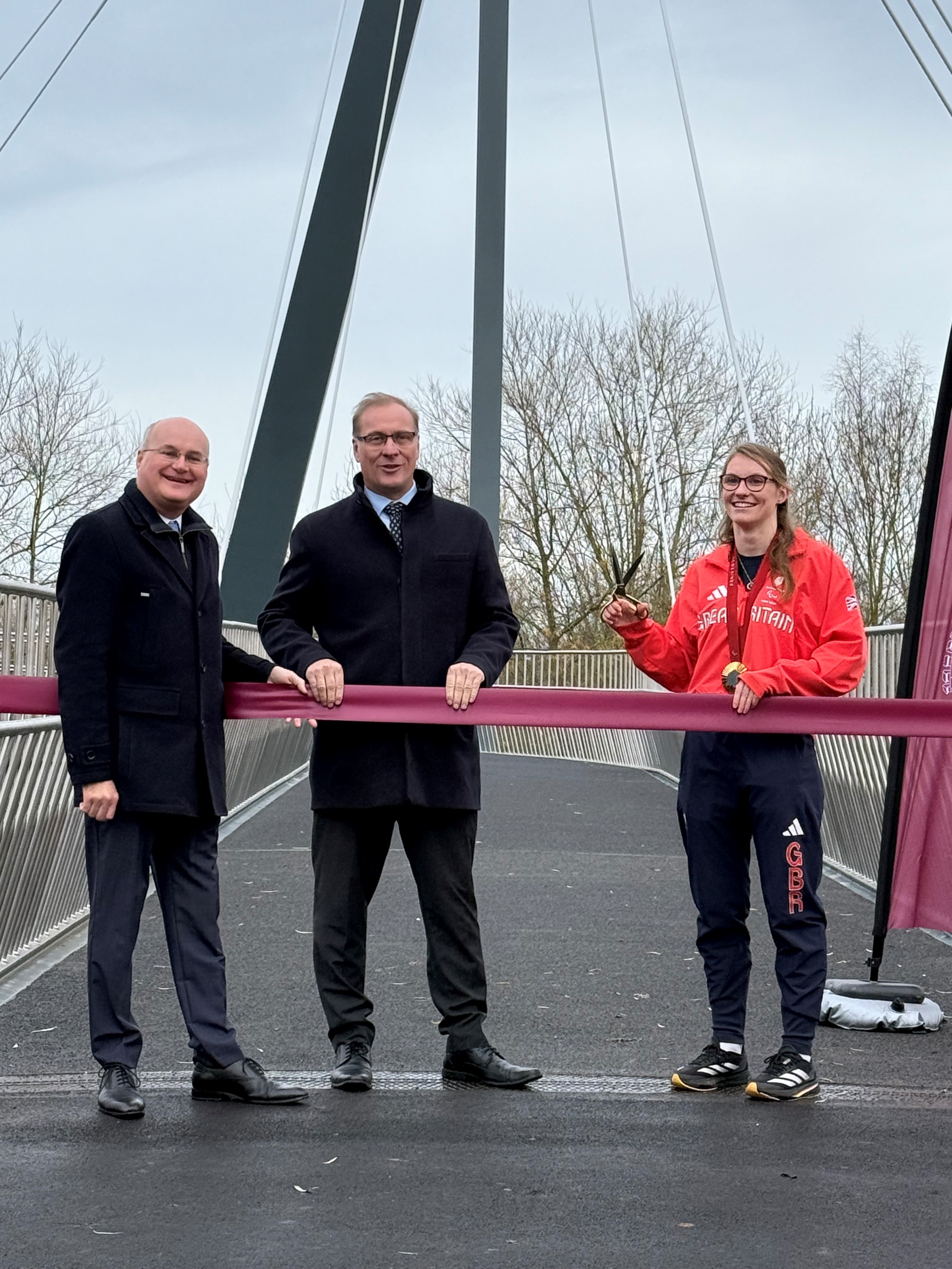 Councillor Simon Geraghty and Councillor Marc Bayliss stood on Kepax Bridge next to the ribbon, with Rebecca Redfern MBE holding the scissors ready to cut the ribbon.