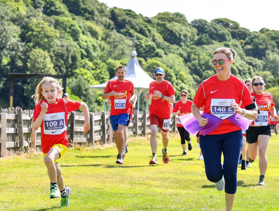Families running together in red t-shirts in a field