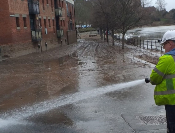 Person jet washing the road following floods