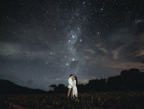 Couple dressed in white under a starry sky in the countryside