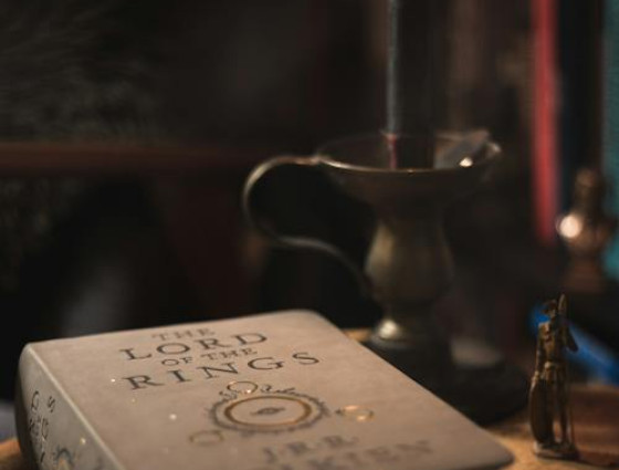 hardback lord of the rings book on a wooden table with a candlestick behind it