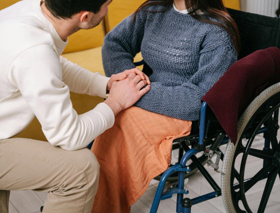 A lady in a wheelchair holding hands with a man