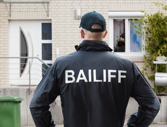 Image of a man wearing a coat with bailiff printed on the back