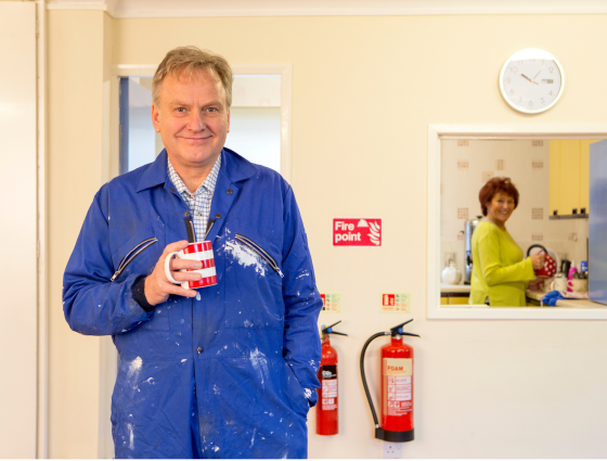 Image of a man in overalls holding a mug