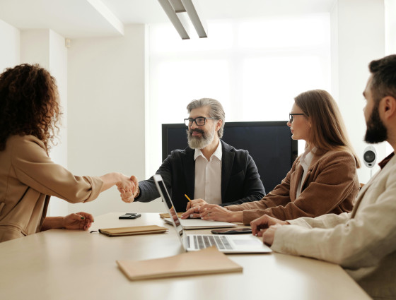 Image of 4 people sat around a table talking and shaking hands