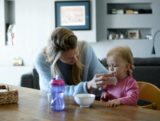 Image of a woman help feed a young child