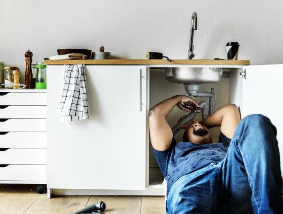 Image of a man lay down fixing a sink