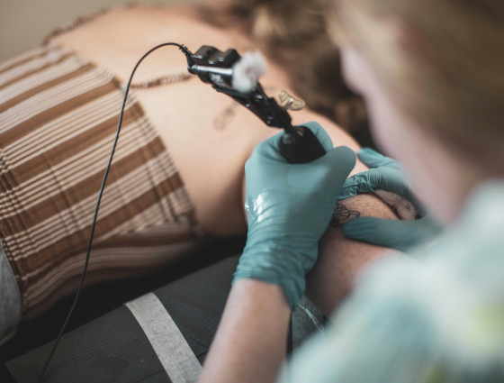 Image of a person tattooing another person's arm