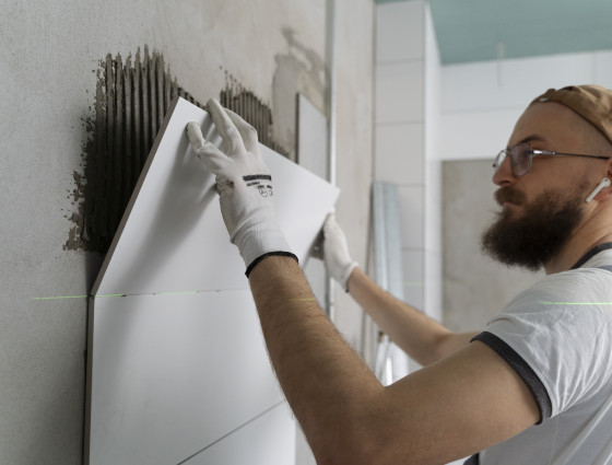 Image of a man fixing tiles to a wall