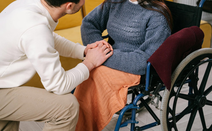 A lady in a wheelchair holding hands with a man
